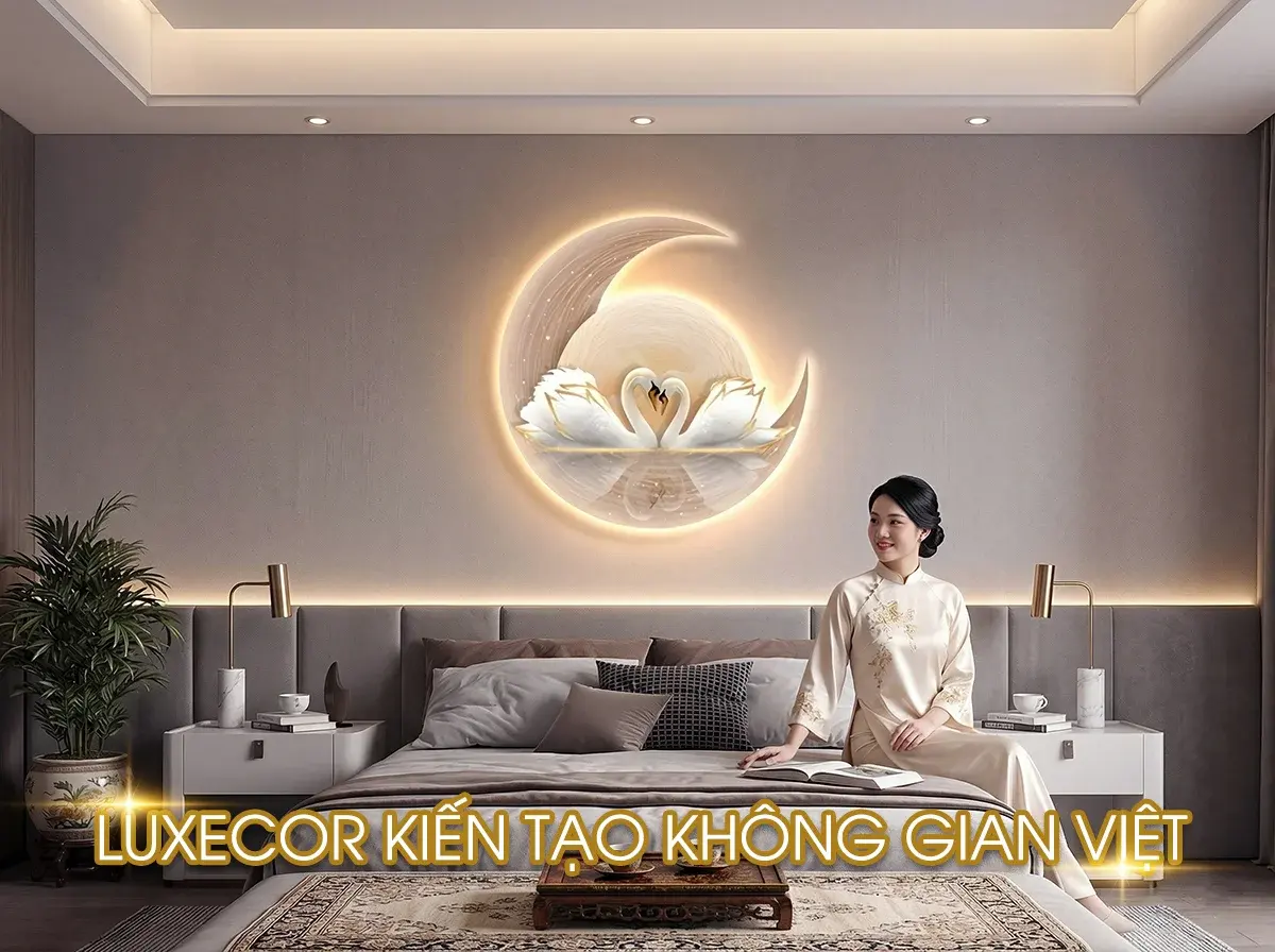 Phụ nữ mặc áo dài ngồi trên giường, phía sau là tranh đèn LED tráng gương đôi thiên nga tạo hình trái tim trên vầng trăng khuyết.