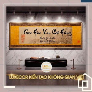 Tranh treo tường Gia Hòa Vạn Sự Hưng nền vàng vân đá cao cấp đặt trên kệ tủ.